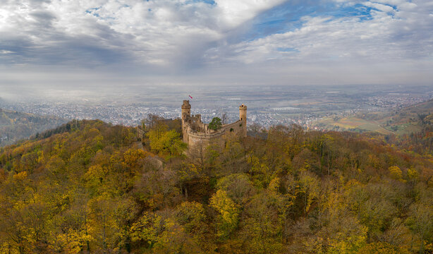 Aerial view of medieval Schloss Auerbach castle ruin atop a hill, surrounded by autumn trees under a cloudy sky, Bensheim, Hessen, Germany.