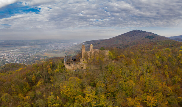 Aerial view of castle Schloss Auerbach ruins perched atop a hill amidst autumnal foliage, contrasting against the distant cityscape, Bensheim, Hessen, Germany.