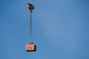Crane Lifting Stack of Bricks Against Blue Sky .  Copy space