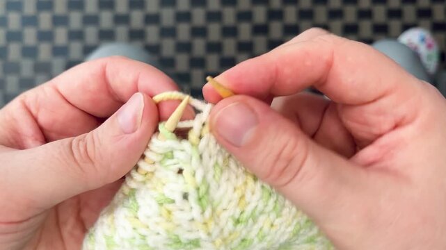 The process of knitting a green and white dog sweater with bamboo knitting needles. Top view. Hobby. Handmade.