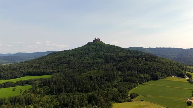 Luftaufnahme Burg Hohenzollern thront auf dem 855 m hohen Hohenzollernberg bei Bisingen in Baden-Wuerttemberg, Deutschland. Eine eindrucksvolle Gipfelburg inmitten gruener Waelder und Felder