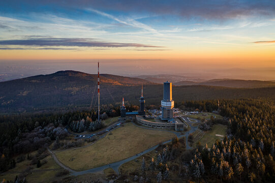 Aerial view of the Taunus mountain range, the iconic Grosser Feldberg tower piercing through the skyline under a vibrant sunset, Schmitten im Taunus, Hessen, Germany.