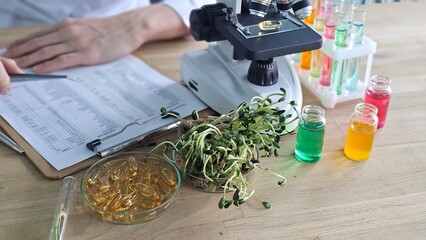 Scientist conducts research using a microscope, plant samples, and colorful solutions in laboratory