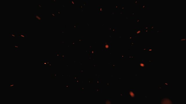 Realistic flying sparks and embers from a bonfire captured on camera. Abstract glowing particles of burning fire against a black background, flashes of bonfire light.