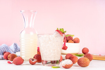 Lychee fruit tasty margarita or lemonade cocktail. Tasty alcohol drink with fresh lychees, mint leaves, liqueur and sweet sour juice, on white pink table background with ripe raw lychee fruits, copy s