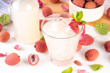 Lychee fruit tasty margarita or lemonade cocktail. Tasty alcohol drink with fresh lychees, mint leaves, liqueur and sweet sour juice, on white pink table background with ripe raw lychee fruits, copy s
