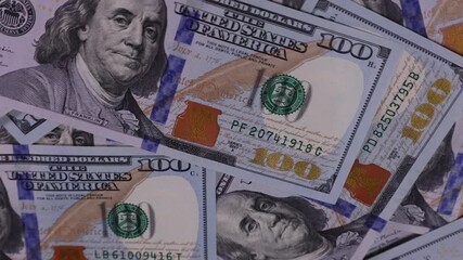 Explore different perspectives of one hundred dollar bills scattered on a surface in close-up views from various angles at a well-lit space