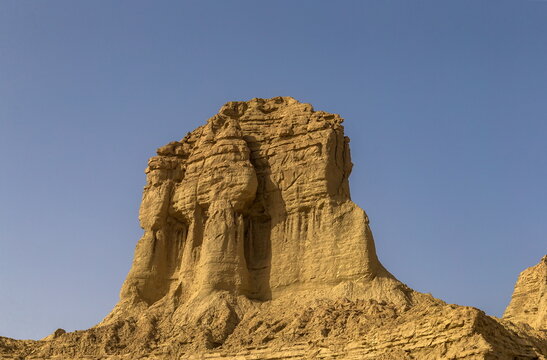 View of stark rock formations rise against the clear blue sky, textures and shadows creating a striking desert landscape, Makran Coastal Highway, Balochistan, Pakistan.