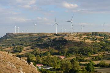 A small village with a few houses and a wind farm in the hill of background