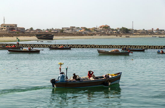 View of vibrant fishing boats dance on the shimmering turquoise water, carrying fishermen against the backdrop of the coastal city, Gwadar, Balochistan, Pakistan.