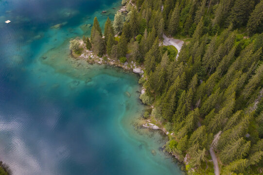 Aerial view of the stunning Cauma See turquoise waters meeting the lush green forest at the shoreline, creating a vibrant contrast of natural beauty, Flims, Grisons, Switzerland.