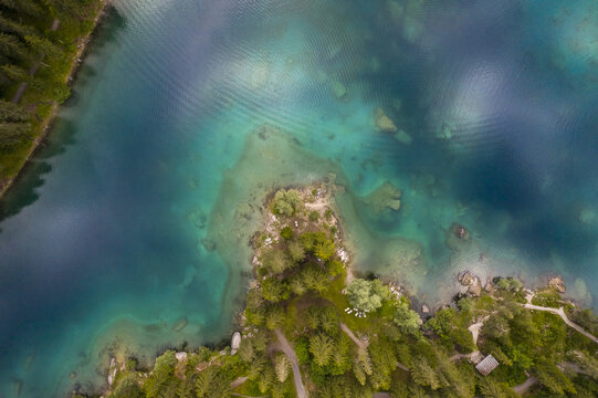 Aerial view of the vivid lake Cauma turquoise waters meeting the lush green shoreline, creating a stunning contrast of colors and textures, Flims, Grisons, Switzerland.