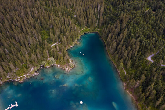 Aerial view of the turquoise waters of Lake Cauma meet the dense, emerald forests in a stunning contrast of natural beauty, Flims, Grisons, Switzerland.