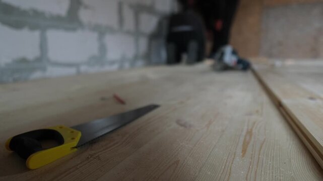 Wood floor installation process. Hand saw and work area during real home construction