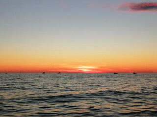 Sunset over the sea, silhouettes of ships on the horizon