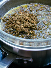 Cannabis Flowers in Melted Butter: Marijuana Bud Infusion Cooking Process Making Cannabis Butter Edible Recipe Close-up