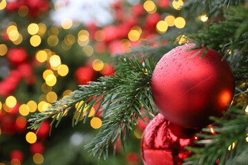 Christmas tree with red toy balls and festive illumination, golden lights on background. New Year tree with toys