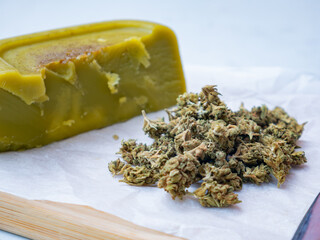homemade cannabis butter and dried marijuana flower buds on a white background, medicinal cannabis...