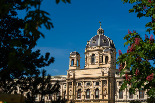 View of the majestic Kunsthistorisches Museum with its grand dome and intricate facade framed by lush greenery in Vienna, Vienna, Austria.
