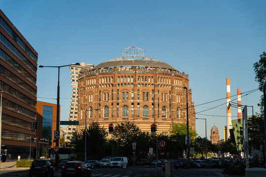 View of the Gasometer, a captivating brick structure with a glass dome, stands amidst modern buildings under a clear sky, Vienna, Vienna, Austria.