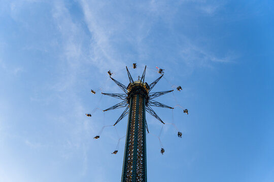 View of a soaring carousel with its seats suspended in mid-air against a backdrop of the clear blue sky, Vienna, Vienna, Austria.