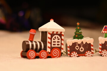 Front part of a decorative wooden Christmas toy train on a light blanket. Close-up of a festive toy locomotive creating a cozy winter holiday atmosphere. © Anastasiia Harbar