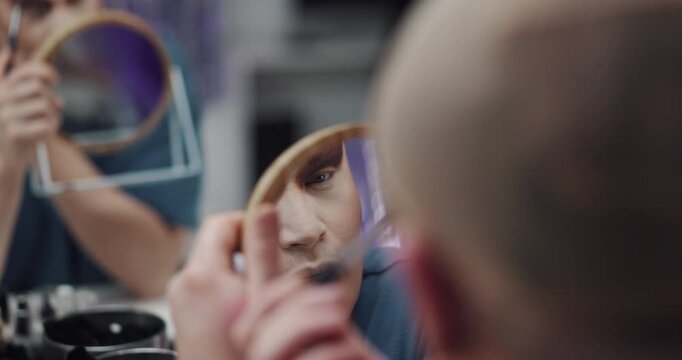 Drag performer, mirror and person with makeup in dressing room for beauty, aesthetic and self expression. Backstage, lgbtq and artist getting ready with cosmetics, eyeshadow or makeover in reflection