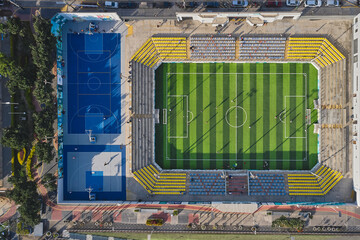 Urban sports complex featuring a vibrant soccer field and blue basketball courts seen from above © rjankovsky