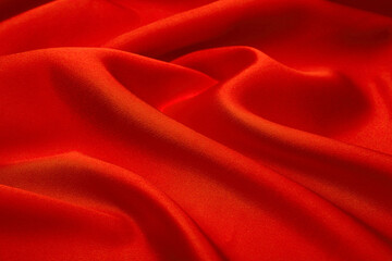 Bright red satin fabric texture with shimmering folds, luxurious silky textile perfect for glamorous design, fashion, beauty branding, and elegant packaging.