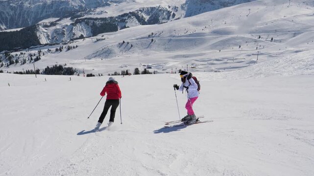 Skier skis down a downhill. Swears and shakes fist at another skier who is standing dangerously in center ski slope. Beautiful alpine landscape and bright sunshine create perfect day winter mountain