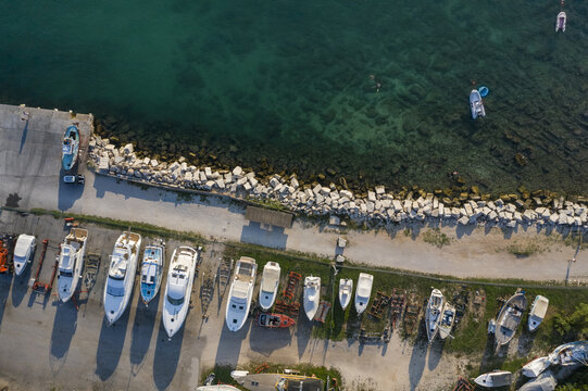 Aerial view of boats moored along the pier, contrasting with the turquoise waters and the rugged shoreline, Rovinj, Istria County, Croatia.
