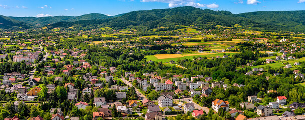 Aerial panoramic view of disperse housing of residential district of Andrychow city along railway track with Beskidy Mountains in background in Lesser Poland