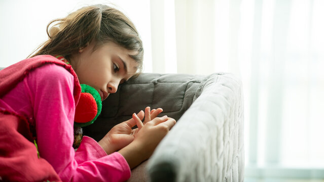 Sad little girl sitting alone on a sofa at home, showing loneliness, childhood emotions, mental health awareness, quiet moment, and emotional lifestyle concept indoors.
