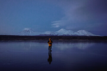 Naklejka premium A Man on a Frozen Lake with a View of Kamchatka Volcanoes