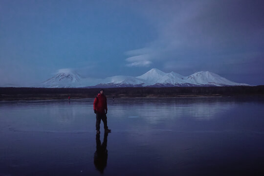 A Man on a Frozen Lake with a View of Kamchatka Volcanoes