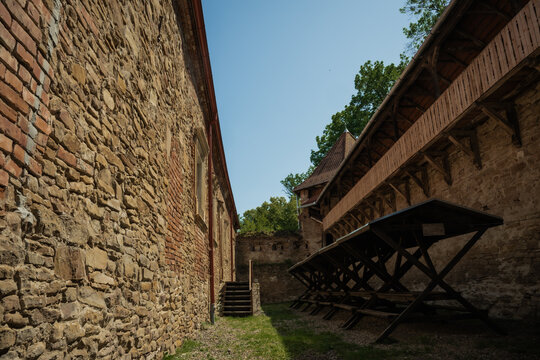 View of weathered stone walls rise majestically, casting shadows on the courtyard, ancient history etched into every brick, Cris, Transilvania, Romania.