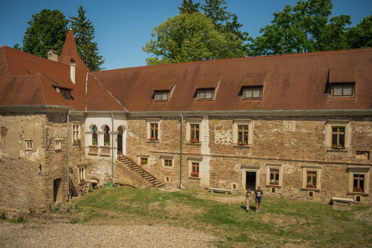View of the imposing Bethlen Castle, with its red tiled roof and stone walls, stands majestically against a backdrop of lush green trees, Cris, Transilvania, Romania.