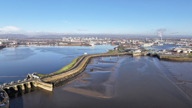 Aerial view of a tranquil waterway reflecting the clear sky, the Cardiff Bay Barrage Locks standing firm against the gentle current, Cardiff, Wales, United Kingdom.
