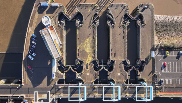 Aerial view of the Cardiff Bay Barrage Locks, a symphony of concrete and water, reflecting the stark winter light, Cardiff Bay, Wales, United Kingdom.