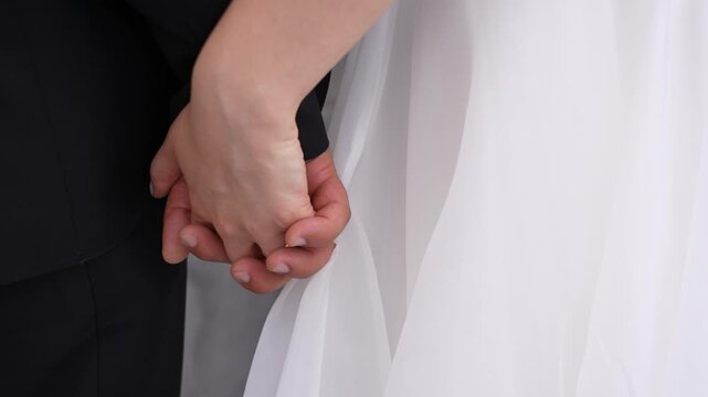 Young married couple holding hands, wedding ceremony