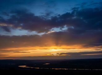 A beautiful orange and blue sunset sky reflects over the sea and city landscape as summer sunlight glows through red and yellow clouds on the horizon