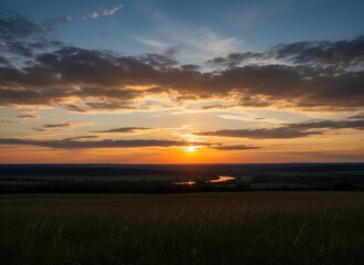A beautiful orange sunset reflects over the calm water of the lake and river under a twilight sky where the sun meets the horizon in a colorful nature landscape