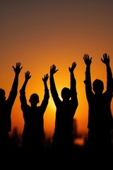 Silhouetted group celebrating at sunset with raised hands