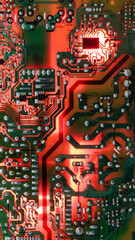 Dusty green circuit board lit by intense red light, highlighting power tracks and solder points for a dramatic technology background.