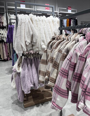  Demi-season pastel-colored clothes are hanging on hangers in the store. Sweatshirts, shirts, and...