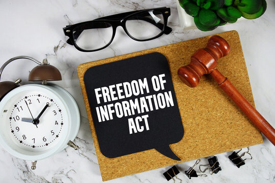 Freedom of Information Act (FOIA) text on speech bubble with alarm clock and wooden gavel on marble background