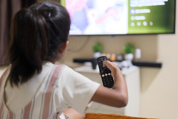 Child watches TV while holding remote control in living room