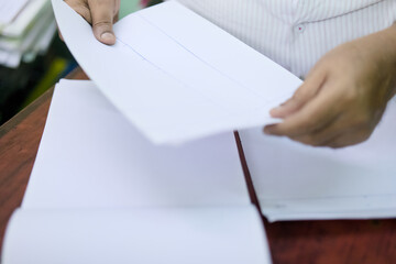 Folding blank sheets of paper on a wooden table