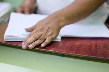 Hand reaching for stacked papers on a wooden table