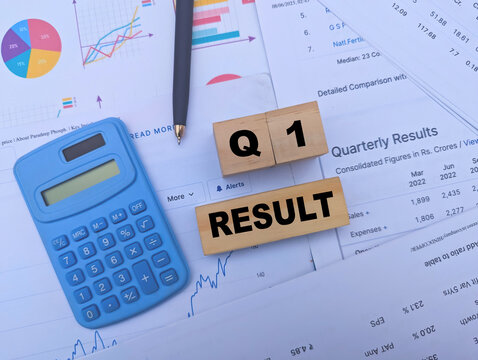 Q1 Result text on wooden blocks with blue calculator and financial charts for business analysis